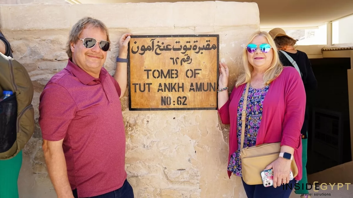 A couple of middle-aged tourists create lasting memories during their Egypt travel experience with a photo in front of the iconic tomb of Tutankhamun 