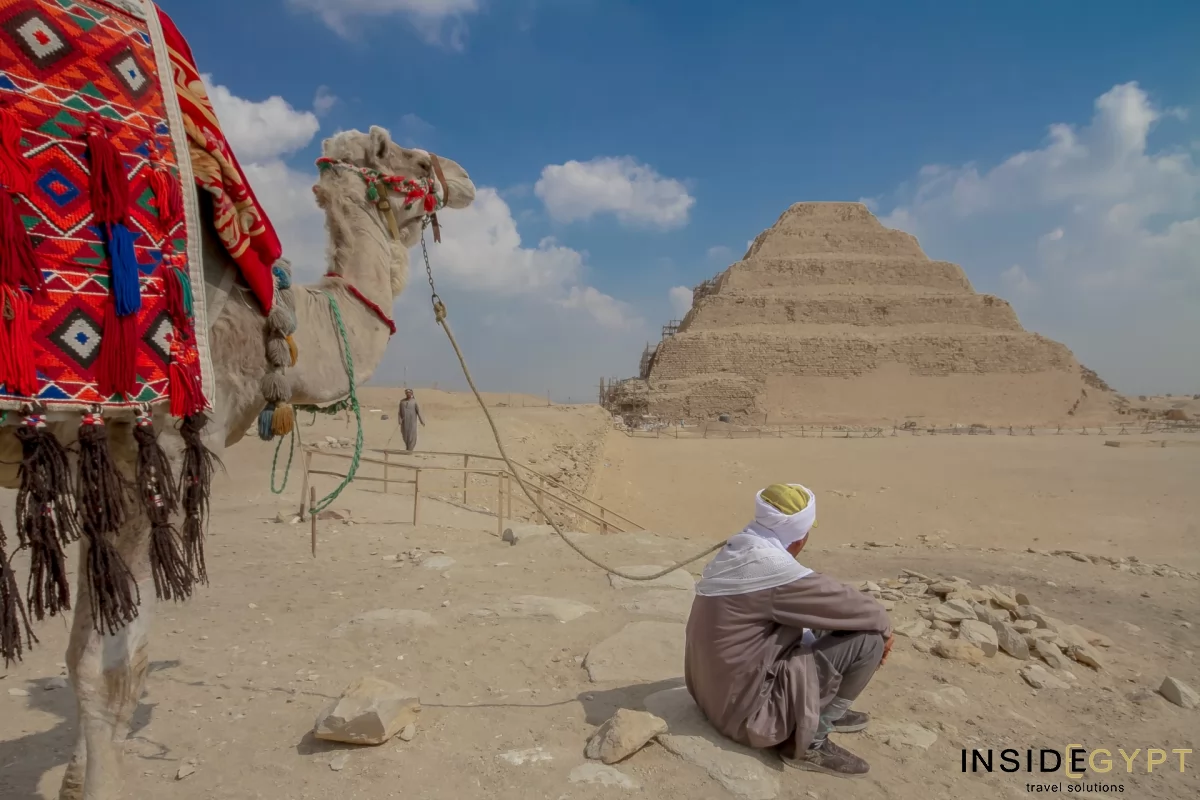 Bedouin and his camel looking at the stepped pyramid of Djoser