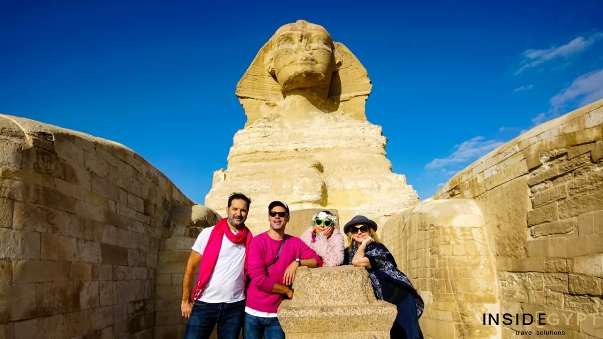 Four tourists capture their unforgettable Egypt travel experience with a photo in front of the awe-inspiring Great Sphinx. 