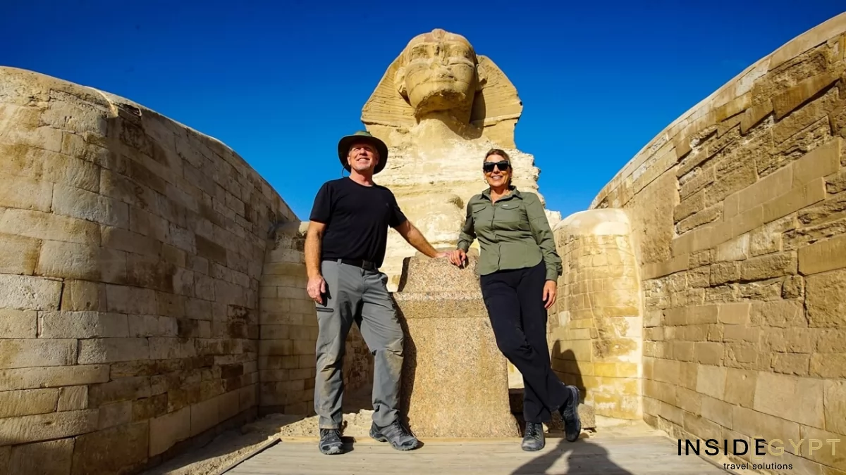 A couple of middle-aged tourists create lasting memories during their Egypt travel experience with a photo in front of the iconic Great Sphinx. 